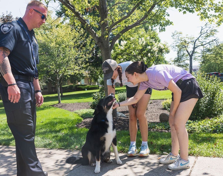 Two Case Western Reserve University students pet the CWRU K-9 officer Maverick