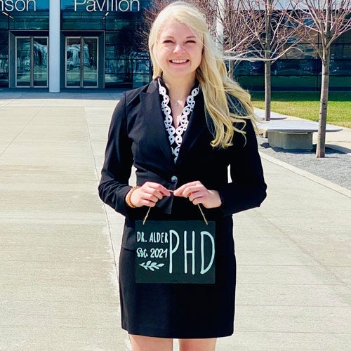Photo of Megan Alder holding a sign that says "Dr. Alder est. 2021 PhD"