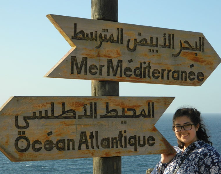 Student standing next to a sign with the words Atlantic Ocean in several languages