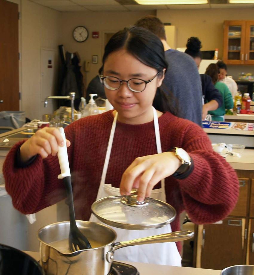 Photo of a student stirring a pot of food during a volunteer opportunity