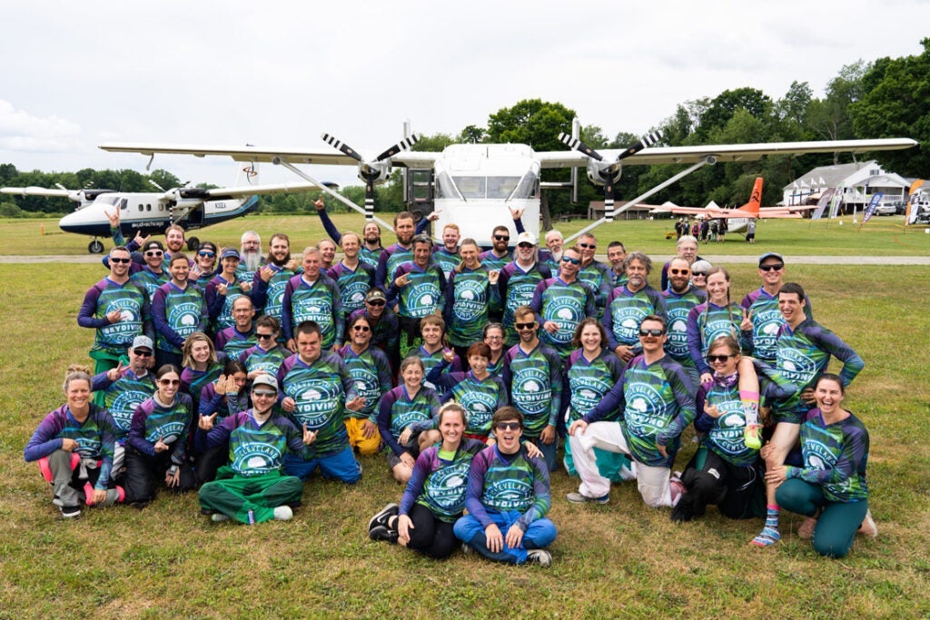The group of skydivers from the record formation pose for a photo in front of a plane