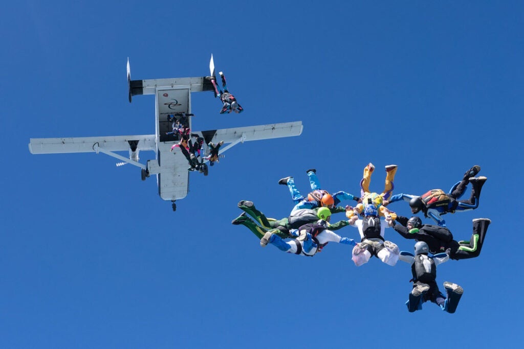 Photo of a group of skydivers jumping from a plane and taking formation