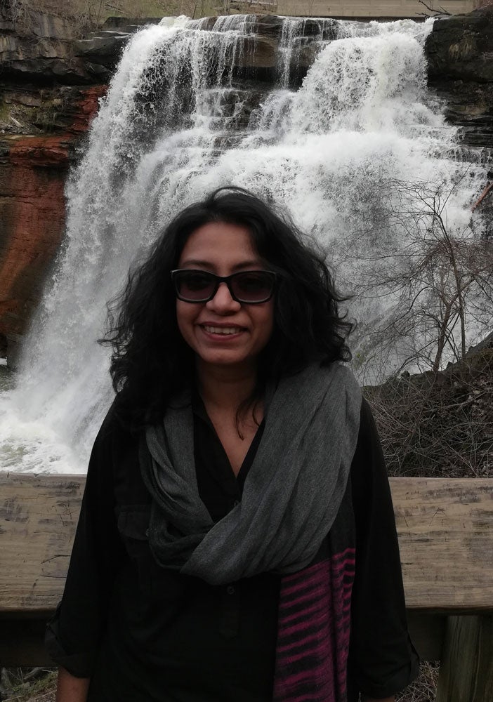 Photo of Reema Sen posing for a photo in front of a waterfall