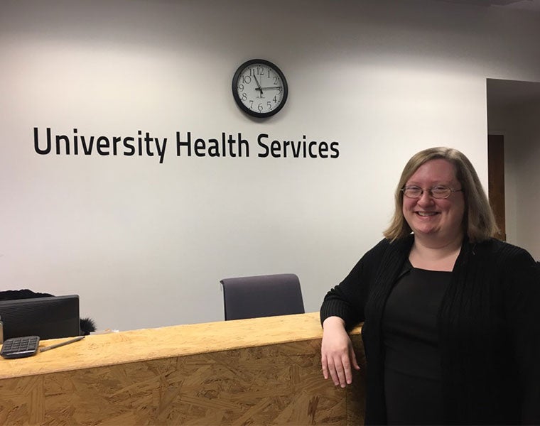 Sara Lee stands at front desk of University Health Services