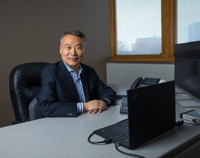 Photo of Shuo Li and two members of his research team looking at medical imaging on a computer screen