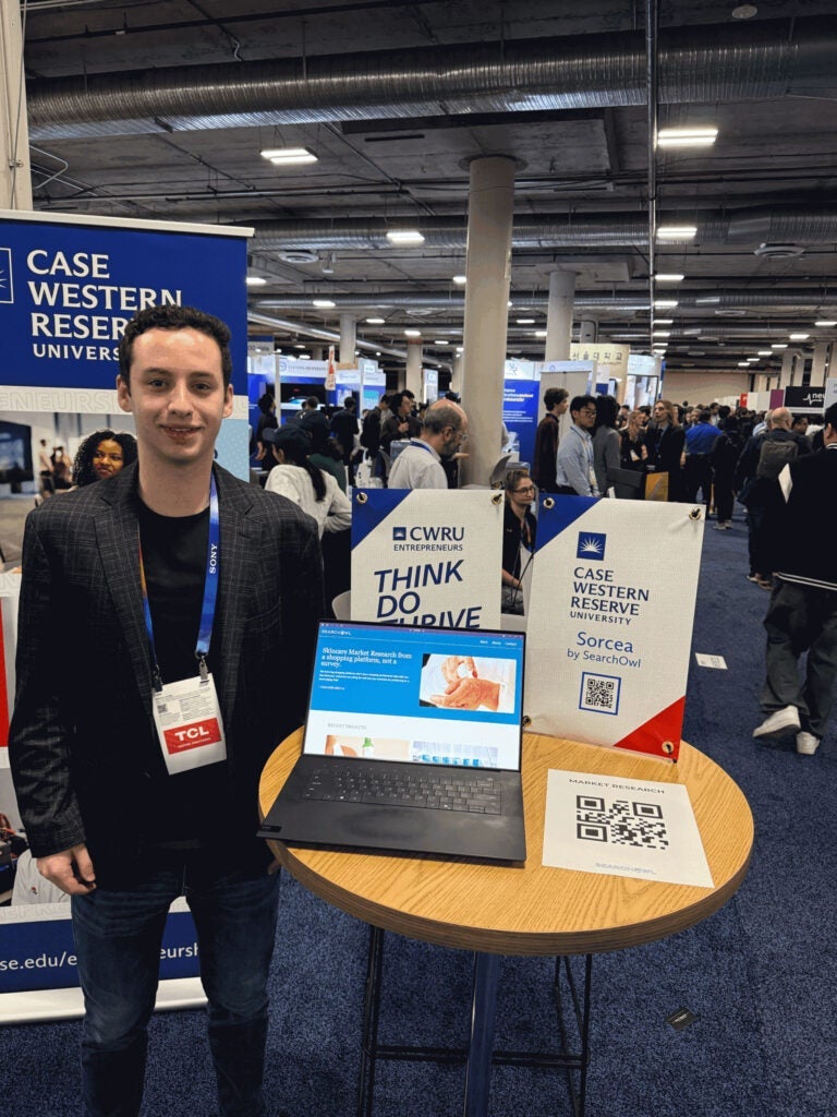 Photo of a CWRU student showcasing his innovation, SearchOwl, at CES