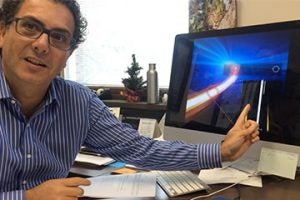 professor Giuseppe Strangi talking at his desk,