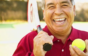 adult male holding tennis racquet and ball