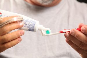man with prosthetic arm squeezing toothpaste