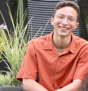 Photo of Case Western Reserve University student Victor Sanchez Franco sitting outside in front of a plant