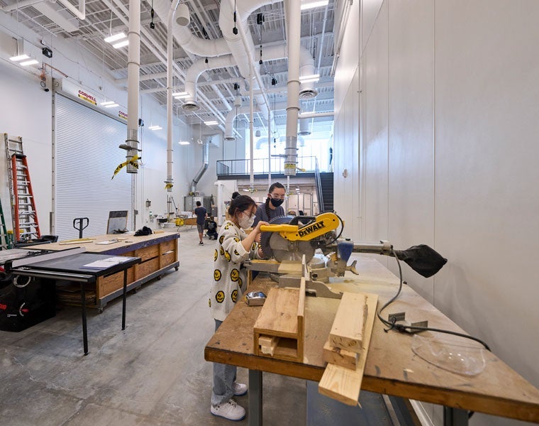 Photo of two students using a miter saw in the workshop