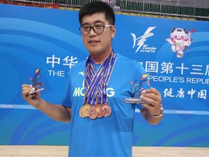 Ye "Duke" Li with multiple medals and holding a trophy in each hand
