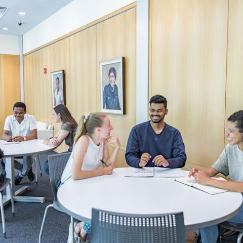 Two tables of students in Mandel Center talking