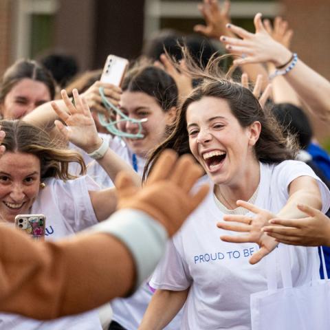 Students rush to high five and clap hands with Spartie