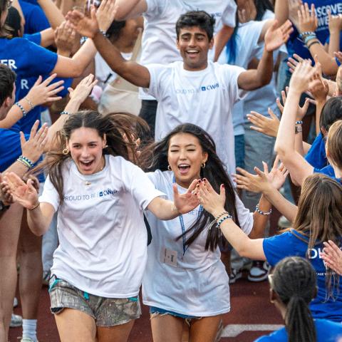 Photo of CWRU Class of 2029 students running through a tunnel of orientation leaders during Discover Week