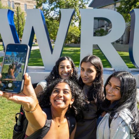 A group of students take a selfie near the big CWRU letters on the first day of classes.