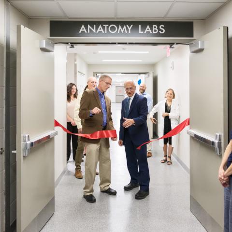 Stan Gerson and Darin Croft cutting a red ribbon at the doors of the new anatomy lab