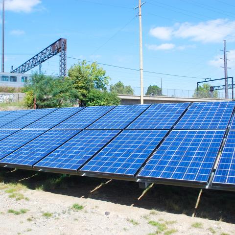 Photograph of rows of solar panels aligned in a field at a photovoltaic power plant in Cleveland.