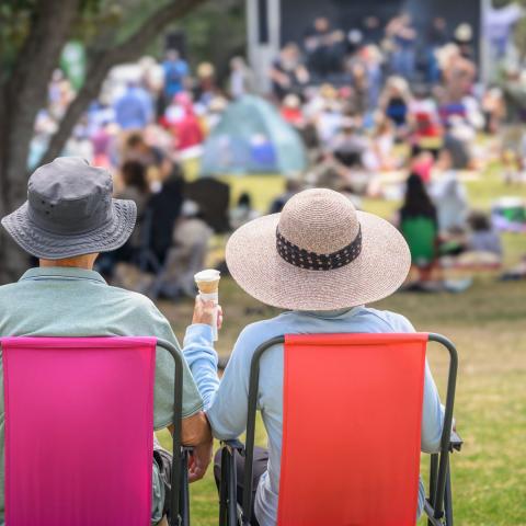Photo of an elderly couple sitting next to one another in lawn chairs at an outdoor event