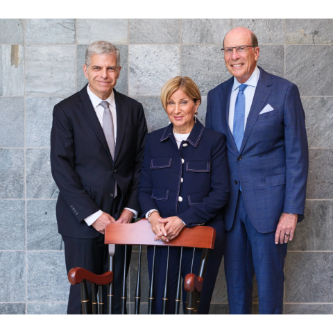 Three people standing behind a chair