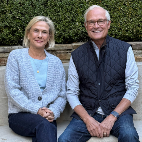 Lady in a blue sweater sitting next to a man with a vest outside
