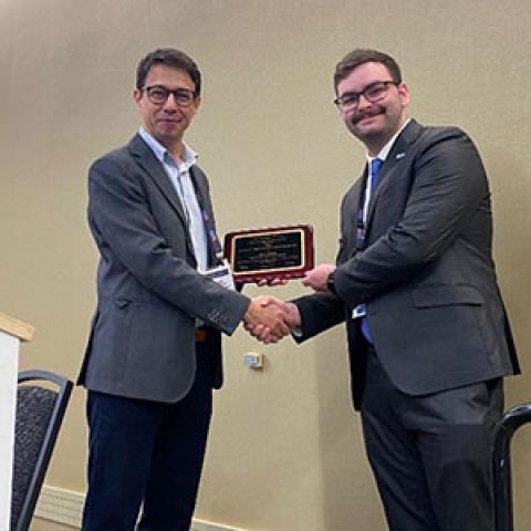 Photo of two men shaking hands as one accepts an award