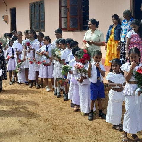 Village children of Boralanda standing in front of a building holding flowers