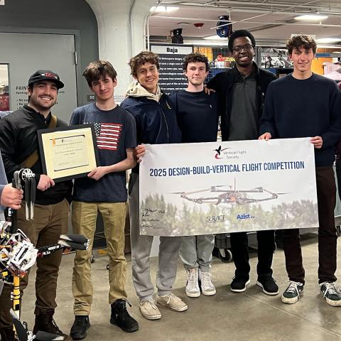 Members of VTOL gather for a photo with their team banner