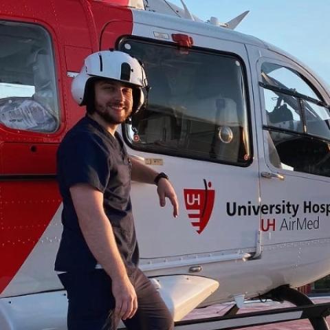 CRNA student Robert Sharkey stands in front of a medical helicopter on a rooftop.