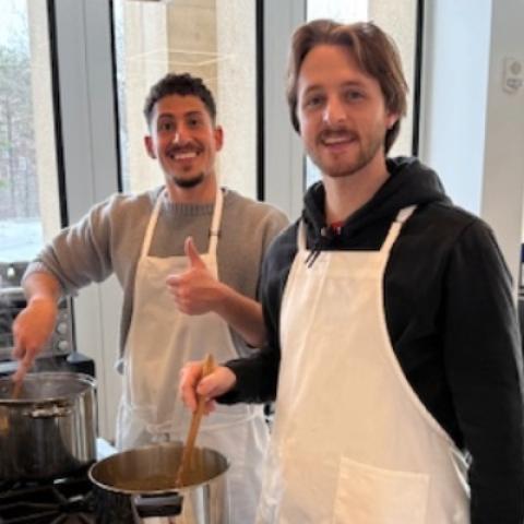 three students smiling together while cooking in the teaching kitchen