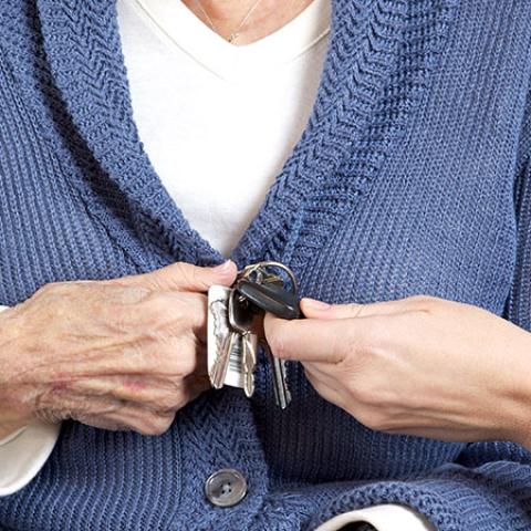 Photo of an elderly woman handing car keys to another person