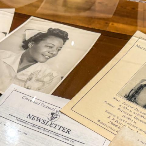 A selection of papers feature photos of Black nurses are spread out in a display case.