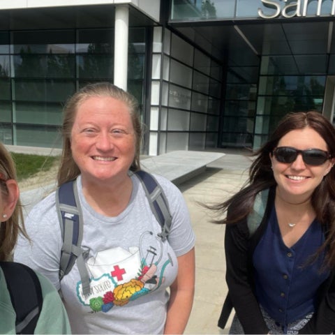 Four women smile at the camera in front of Samson Pavilion.