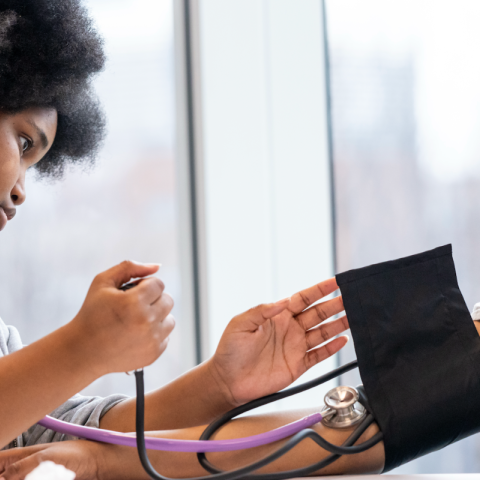 A student wearing a stethoscope checks the blood pressure on another student.