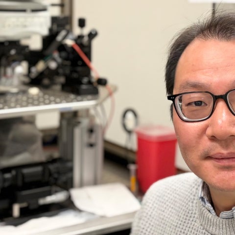 A scientist sits next to a patch clamp electrophysiology setup