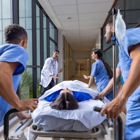 Healthcare workers rushing a patient in a gurney to the emergency room