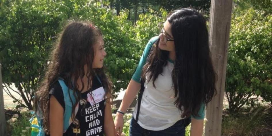Childhood photo of Isabela and Maya Carroll wearing bookbags