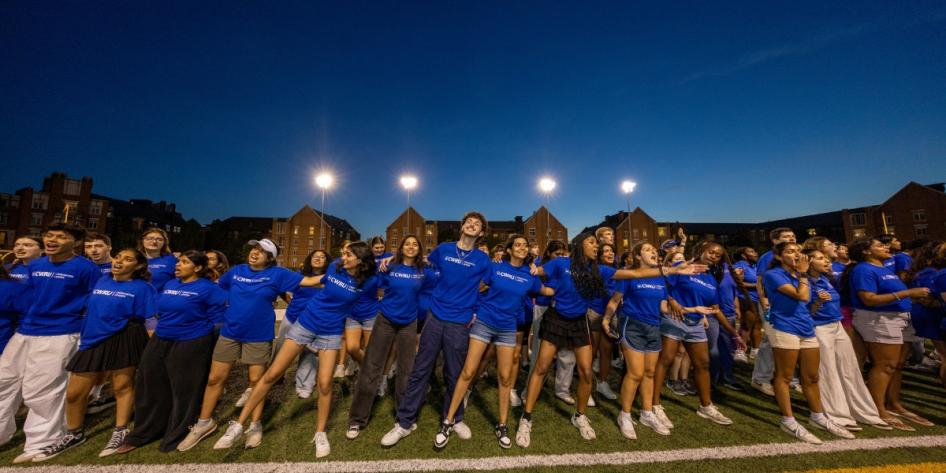 Orientation leaders link arms and belt out tunes at DiSanto Field to give new and transfer students a warm Discover Week welcome.