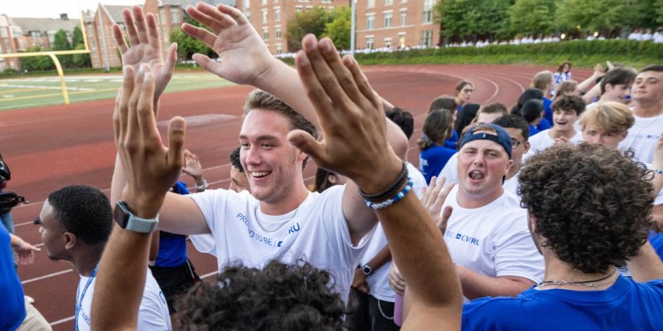 New and transfer students share high fives with CWRU orientation leaders at DiSanto Field.