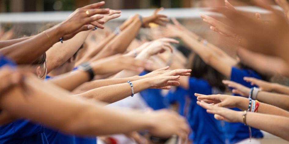 Orientation leaders form an energetic tunnel of arms at DiSanto Field, cheering on new and transfer students as they step onto campus.