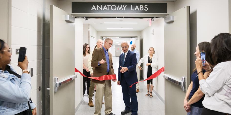 Stan Gerson and Darin Croft cutting a red ribbon at the doors of the new anatomy lab
