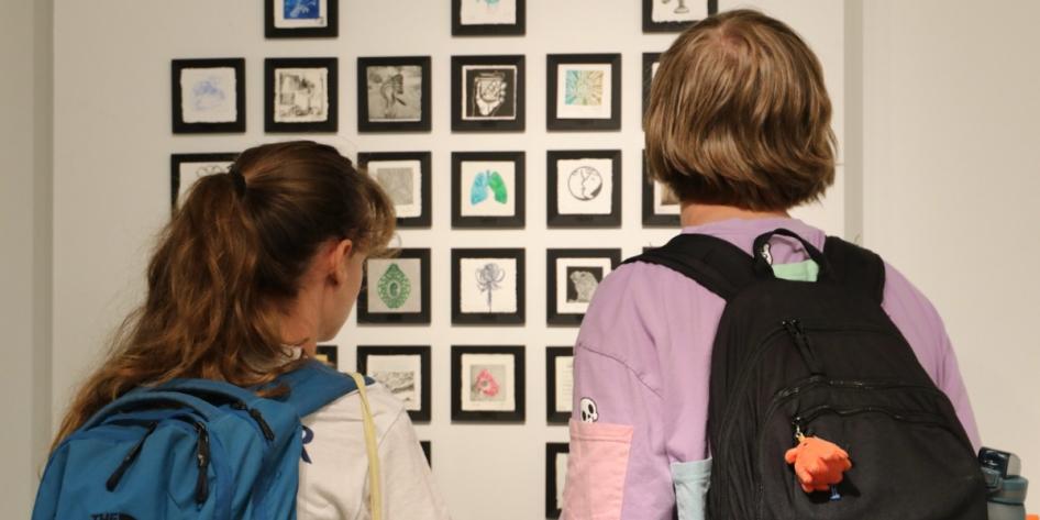 Two students look at a display at Sears think[box]'s Open Print Exchange exhibit.