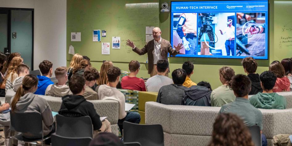 Photo of Mark "Puck" Mykleby leading a presentation for high school students