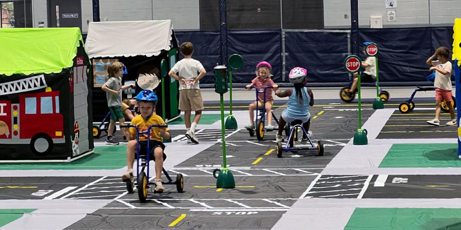 Photo of children riding tricycles around a model town in the Veale Convocation, Recreation and Athletic Center