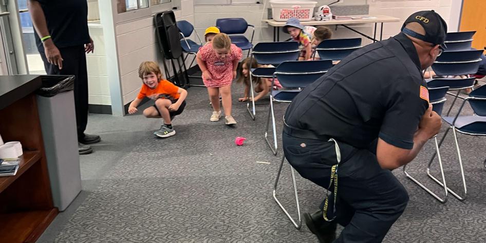 Children crouch down in a room to practice fire safety skills