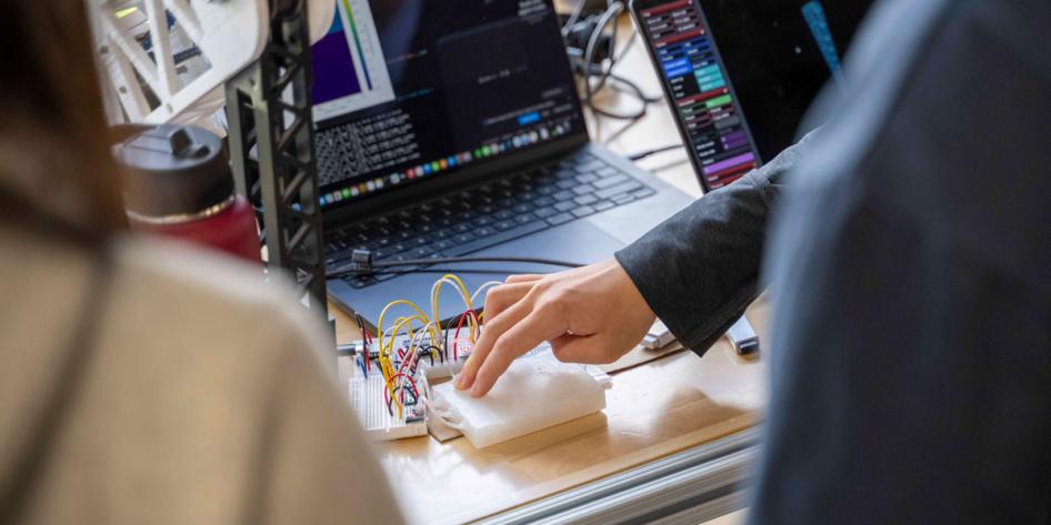 Close up photo of a person placing two fingers on a pad connected to wires
