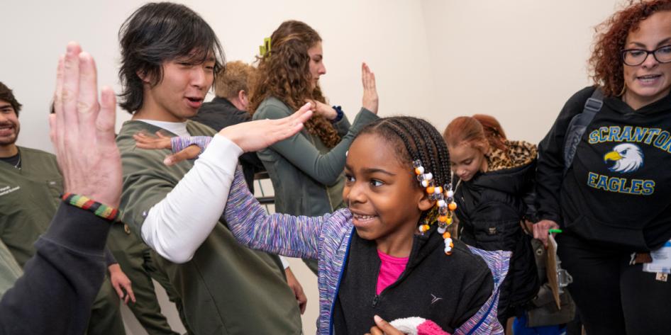 An elementary school student gets a high five from a first-year dental student.