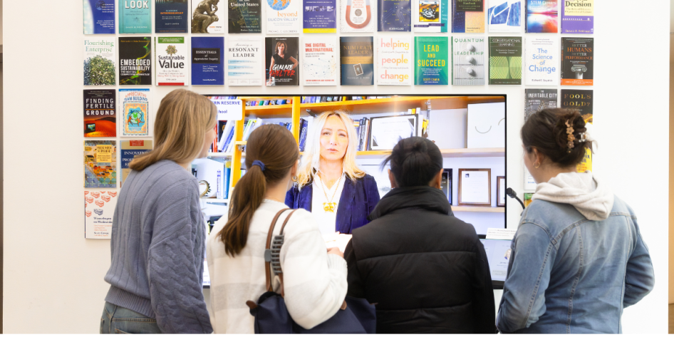 Students gathered around lobby avatar display screen in Weatherhead