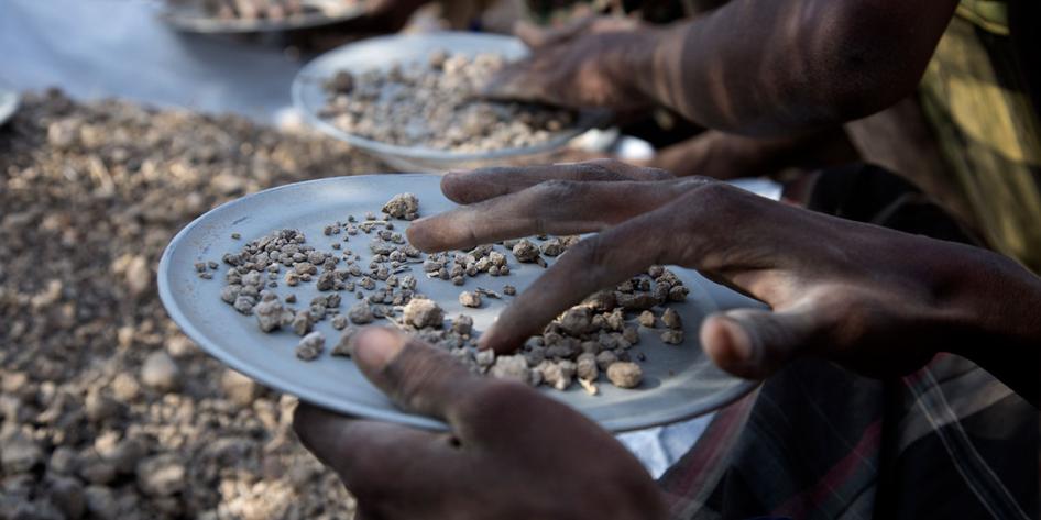Close up image of people sifting through dirt in the field