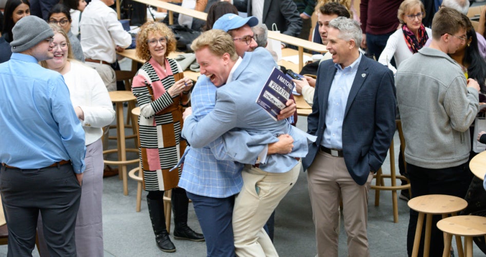 two students hugging as they open their match day envelopes